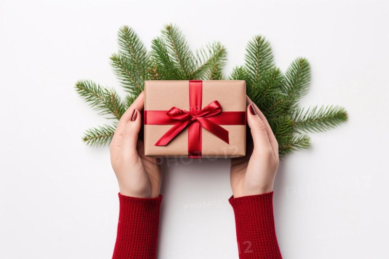 Top view of woman's hands holding christmas gift wrapped in craft paper and red ribbon. KI generiert, generiert, AI generated