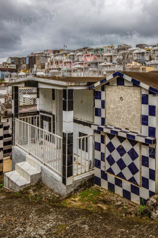 Famous cemetery, many mausoleums or large tombs decorated with tiles, often in black and white. Densely built buildings under a dramatic cloud cover Cimetiere de Morne-a-l'eau, Grand Terre, Guadeloupe, Caribbean, North America