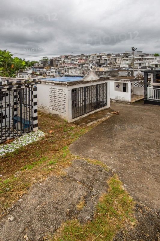 Famous cemetery, many mausoleums or large tombs decorated with tiles, often in black and white. Densely built buildings under a dramatic cloud cover Cimetiere de Morne-a-l'eau, Grand Terre, Guadeloupe, Caribbean, North America
