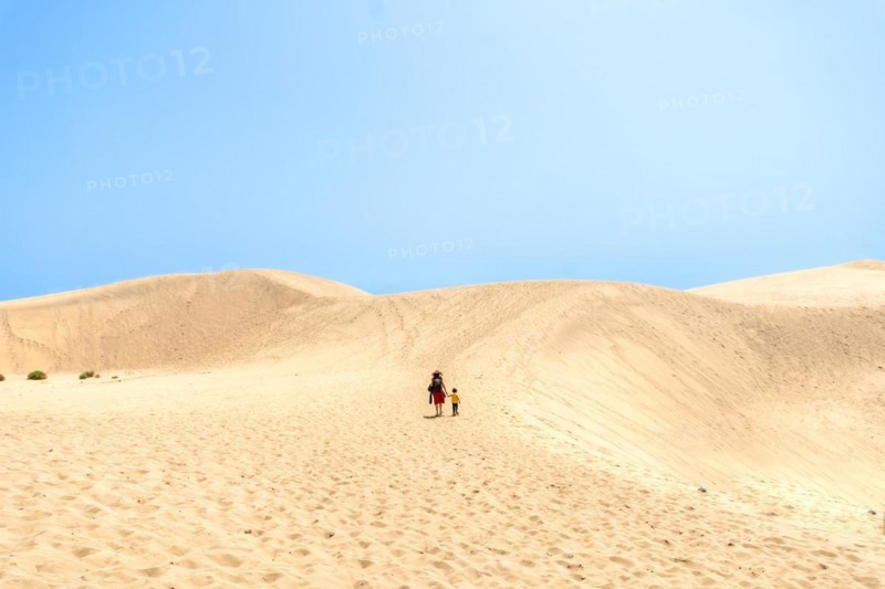 Father and son on vacation smiling in the dunes of Maspalomas, Gran Canaria, Canary Islands