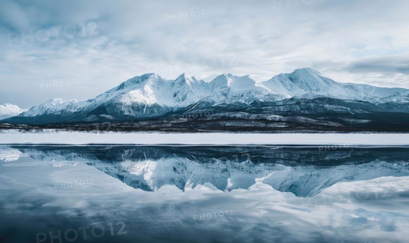 A distant view of snow-capped mountains reflected in the frozen surface of a lake AI generated