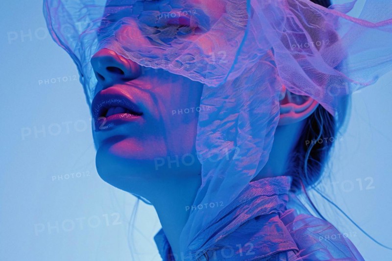 A close-up of a woman's face filtered in blue tones with lace partially covering it, AI generated