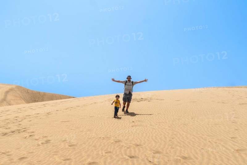 Father and son enjoying going down the dunes of Maspalomas, Gran Canaria, Canary Islands