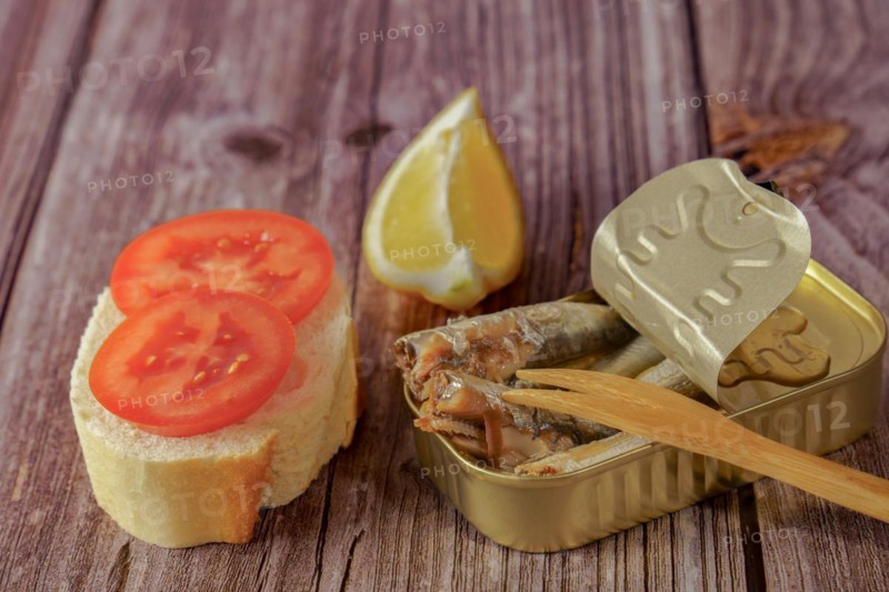 Can of tasty sprats with a slice of bread with tomato and lemon