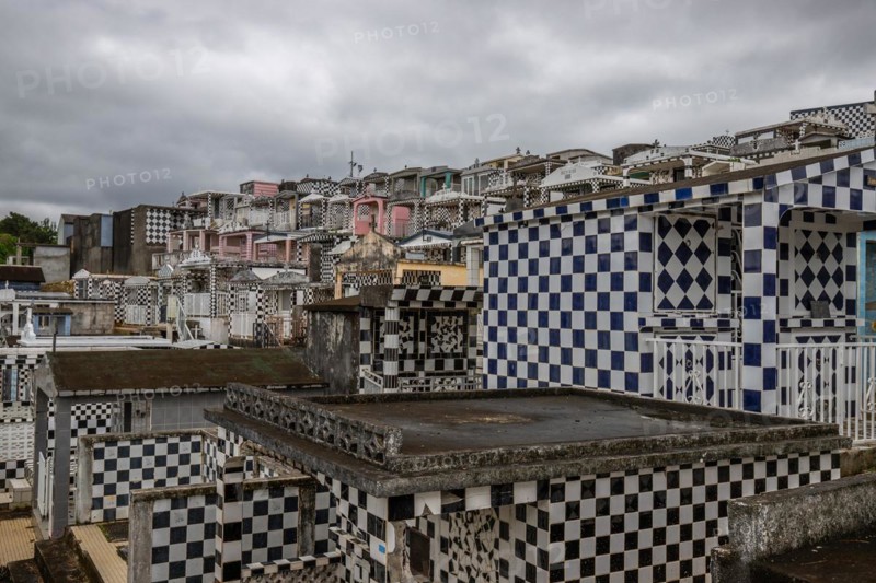 Famous cemetery, many mausoleums or large tombs decorated with tiles, often in black and white. Densely built buildings under a dramatic cloud cover Cimetiere de Morne-a-l'eau, Grand Terre, Guadeloupe, Caribbean, North America