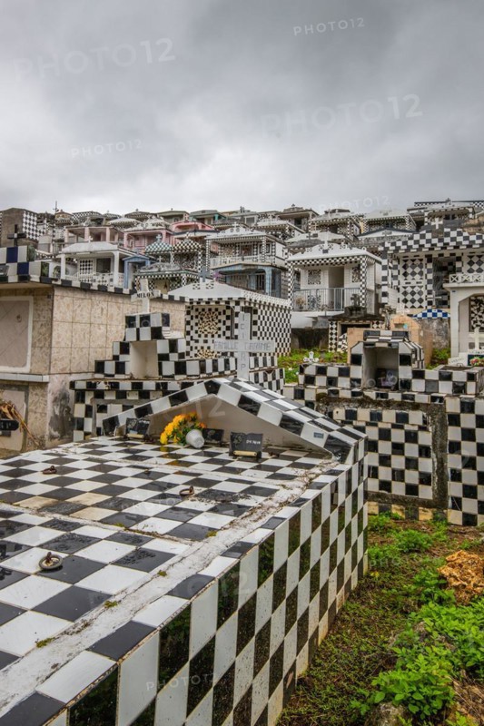 Famous cemetery, many mausoleums or large tombs decorated with tiles, often in black and white. Densely built buildings under a dramatic cloud cover Cimetiere de Morne-a-l'eau, Grand Terre, Guadeloupe, Caribbean, North America