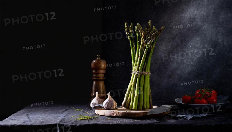 A bunch of green asparagus stands next to a pepper mill and fresh vegetables, fresh green asparagus, KI generated, AI generated