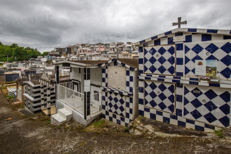 Famous cemetery, many mausoleums or large tombs decorated with tiles, often in black and white. Densely built buildings under a dramatic cloud cover Cimetiere de Morne-a-l'eau, Grand Terre, Guadeloupe, Caribbean, North America
