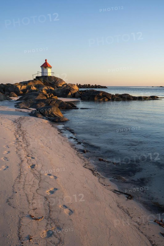 Seascape on the Lofoten Islands. The small lighthouse on the sandy beach of Eggum, sea and rocks. At night at the time of the midnight sun in good weather, blue sky. Golden hour. Early summer. Eggum, Vestvagoya, Lofoten, Norway, Europe