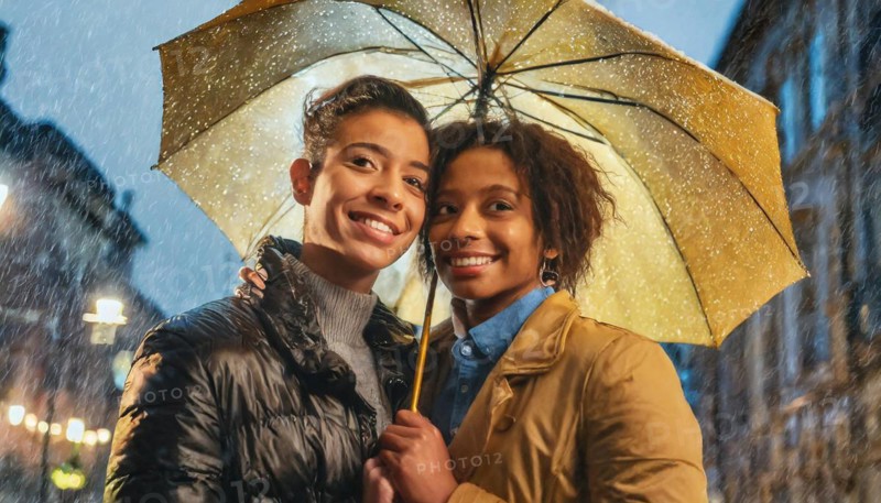 Cheerful couple sharing an umbrella on a rainy city street at night, AI generated