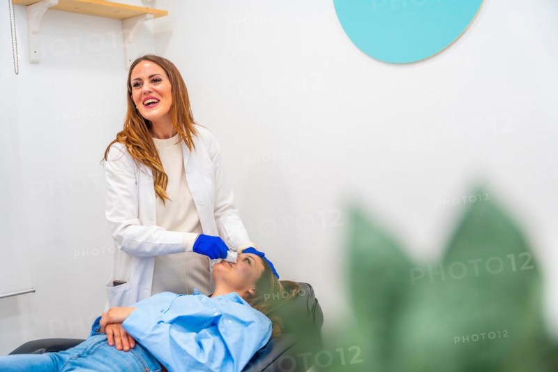 Happy doctor during a beautician treatment in the clinic with a patient