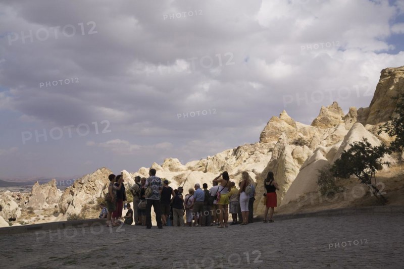 Tourists visiting the rock-cut cave dwellings in Goreme valley, Cappadocia region, Turkey, Asia