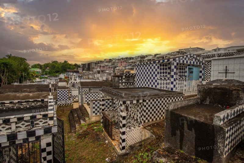 Famous cemetery, many mausoleums or large tombs decorated with tiles, often in black and white. Densely built buildings under a sunset Cimetiere de Morne-a-l'eau, Grand Terre, Guadeloupe, Caribbean, North America