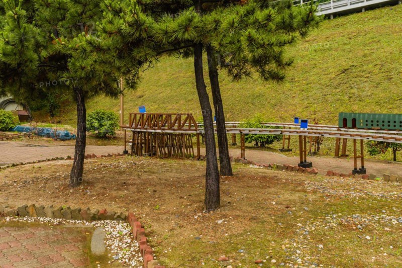 A miniature railway in a park surrounded by trees and footpath, in South Korea