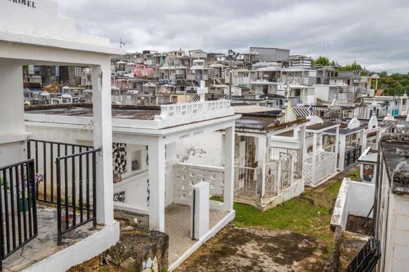 Famous cemetery, many mausoleums or large tombs decorated with tiles, often in black and white. Densely built buildings under a dramatic cloud cover Cimetiere de Morne-a-l'eau, Grand Terre, Guadeloupe, Caribbean, North America