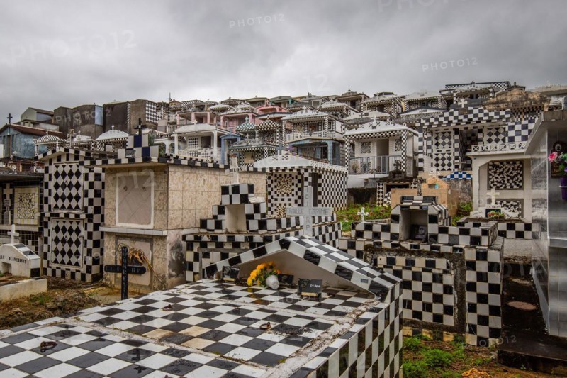 Famous cemetery, many mausoleums or large tombs decorated with tiles, often in black and white. Densely built buildings under a dramatic cloud cover Cimetiere de Morne-a-l'eau, Grand Terre, Guadeloupe, Caribbean, North America