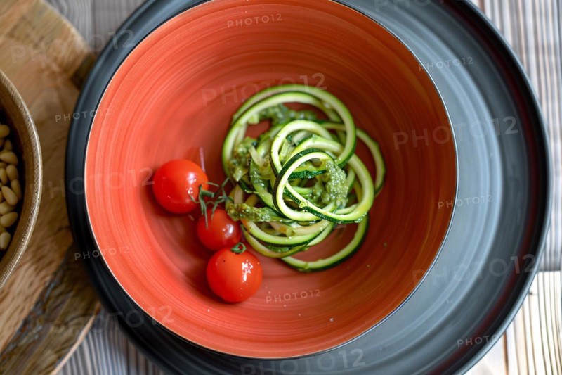 Healthy zucchini noodles with pesto and cherry tomatoes in a vibrant red bowl, AI generated