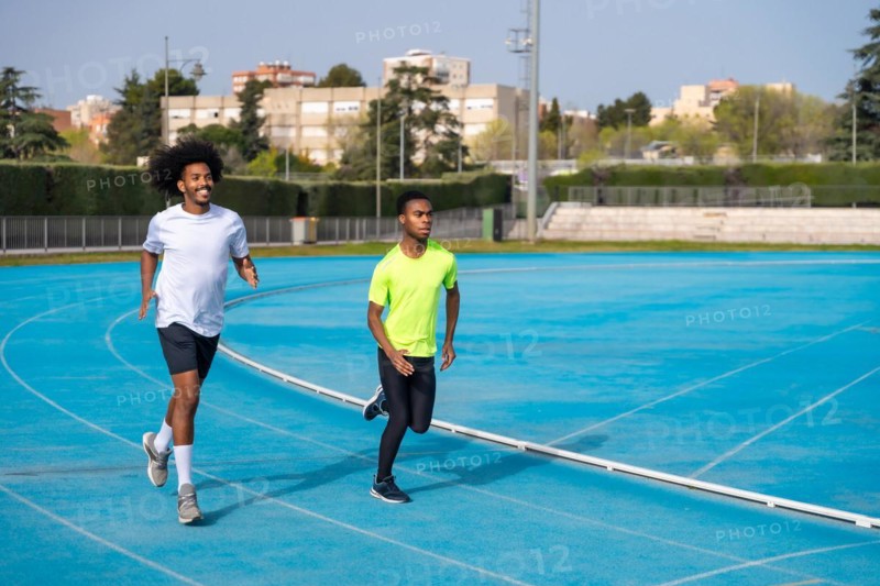Two african american young sports men running together in an outdoor track