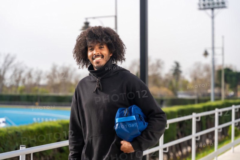 African man going to play pickleball carrying bag with racquet next to the court