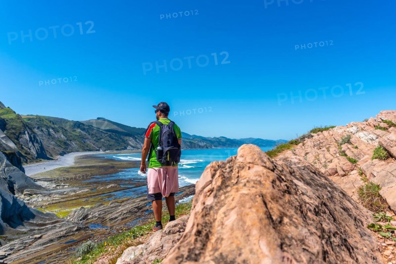 A male hiker in Algorri cove on the coast in the flysch of Zumaia, Gipuzkoa. Basque Country