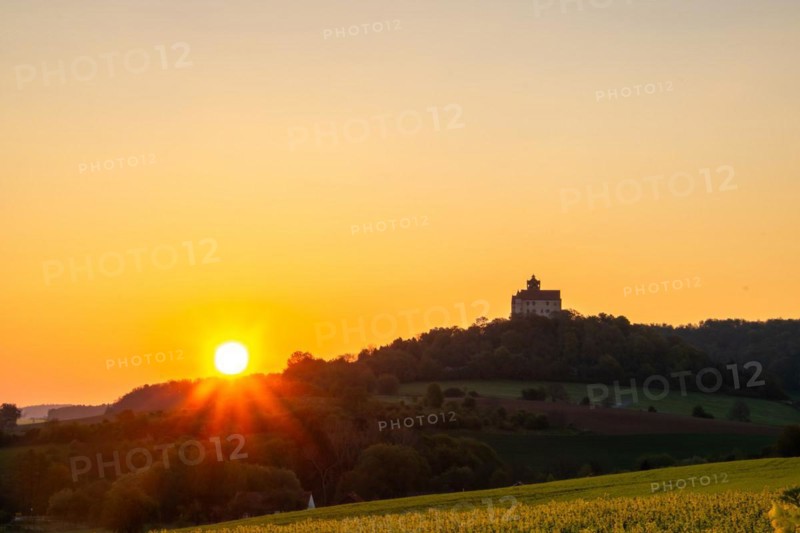 Landscape at sunrise. Beautiful morning landscape with fresh yellow rape fields in spring. Small castle in the yellow fields on a hill. Historic Ronneburg Castle in the middle of nature, Ronneburg, Hesse, Germany, Europe