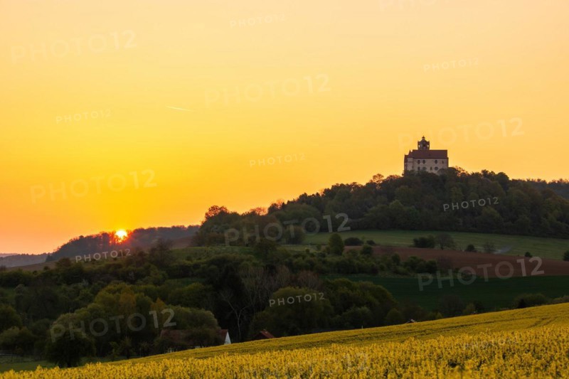 Landscape at sunrise. Beautiful morning landscape with fresh yellow rape fields in spring. Small castle in the yellow fields on a hill. Historic Ronneburg Castle in the middle of nature, Ronneburg, Hesse, Germany, Europe