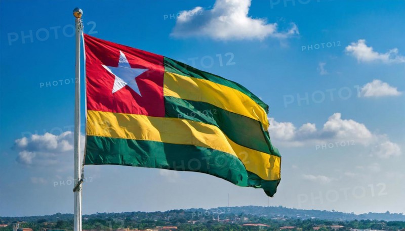The flag of Togo flutters in the wind, isolated against a blue sky