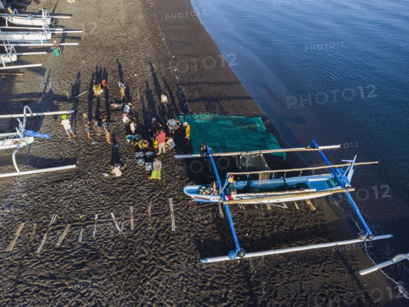 Fishermen unload their catch from their outrigger boat in the morning. Amed, Karangasem, Bali, Indonesia, Asia