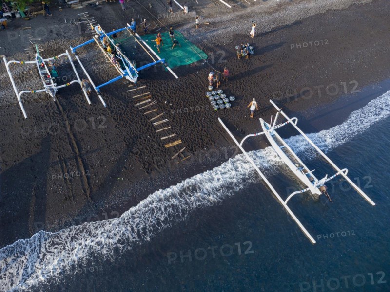 Fishermen unload their catch from their outrigger boat in the morning. Amed, Karangasem, Bali, Indonesia, Asia