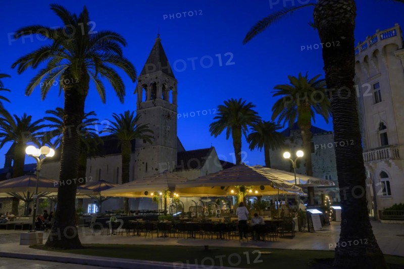 Outdoor restaurant at night with historic church tower and palm trees, Trogir, Dalmatia, Croatia, Europe