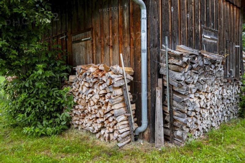 Symbolic image: Firewood stacked in piles at the edges of a shed in a rural area, for example a hut near Maierhoefen in Westallgaeu, Bavaria, Germany, Europe