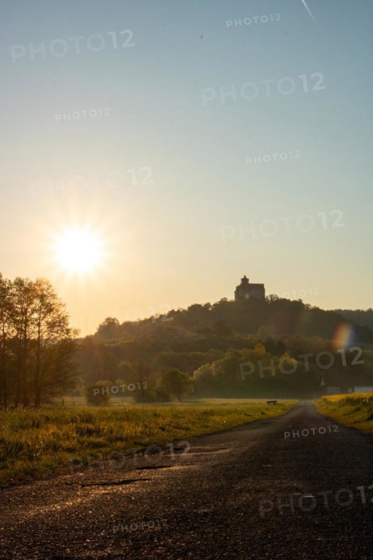 Landscape at sunrise. Beautiful morning landscape with fresh yellow rape fields in spring. Small castle in the yellow fields on a hill. Historic Ronneburg Castle in the middle of nature, Ronneburg, Hesse, Germany, Europe
