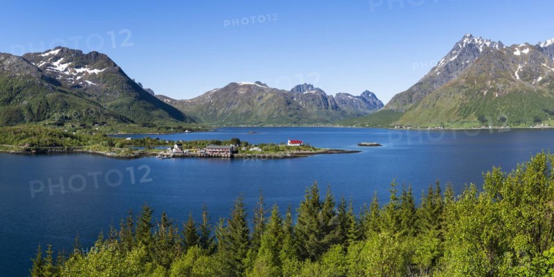 Landscape on the Lofoten Islands with sea and mountains. The Sildpollnes peninsula in the Austnesfjord with a church, a few houses and the Sjocamp campsite. Good weather, blue sky. Early summer. Panoramic shot. Sildpollnes, Austvagoya, Lofoten, Norway, Europe