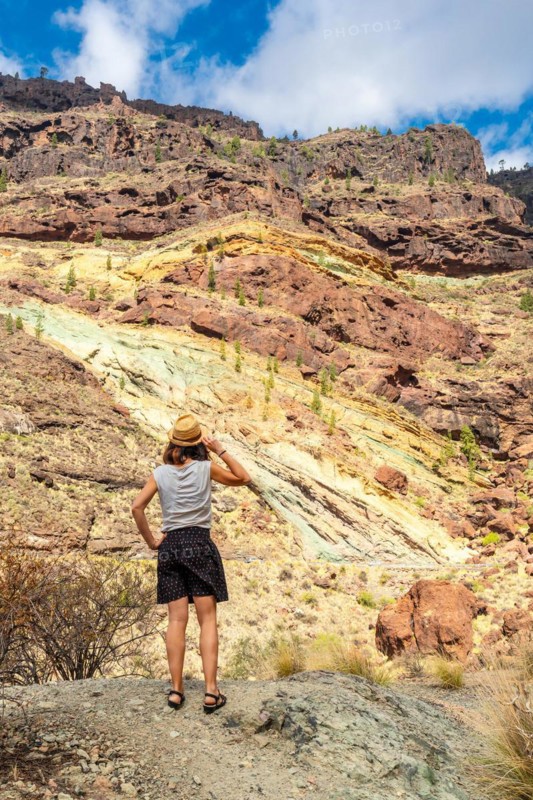 A woman with a hat at the Natural Monument Azulejos de Veneguera or Rainbow Rocks in Mogan, Gran Canaria