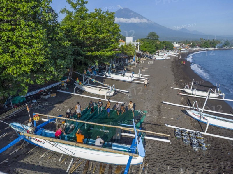 Fishermen loading fish from their outrigger boats in the morning on the black beach of Amed, Mount Agung in the background, Amed, Karangasem, Bali, Indonesia, Asia