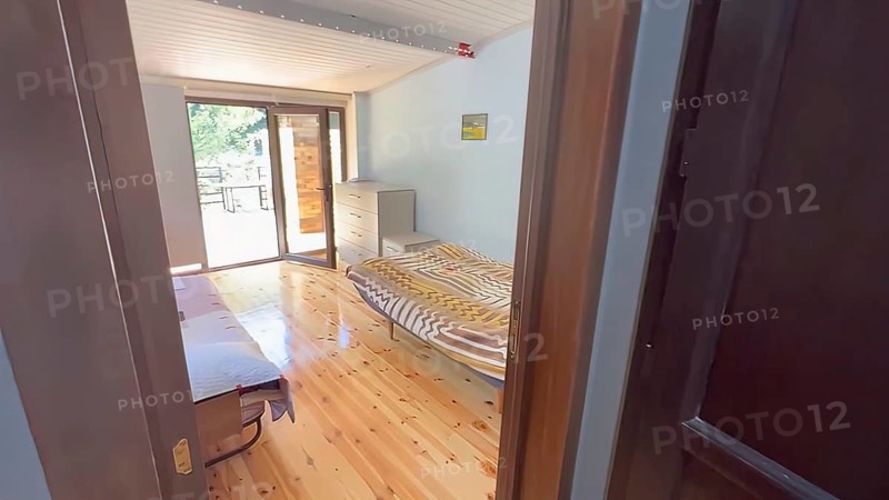 Interior of a bedroom with hardwood floor and wooden bed