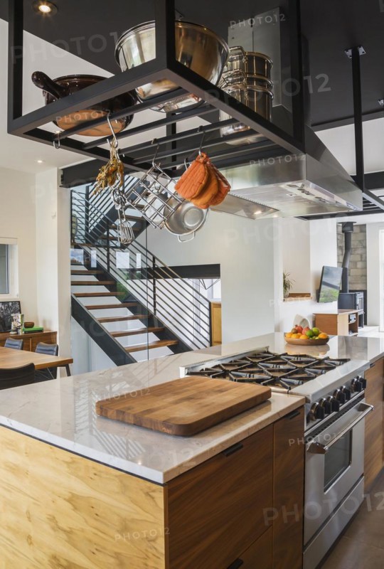 American walnut wood island with quartzite countertop and built-in gas stove in the kitchen inside modern cube style home, Quebec, Canada, North America