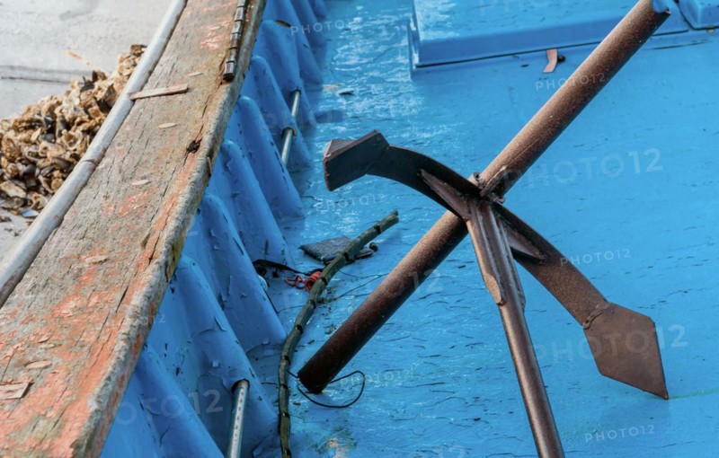 Metal anchor laying on deck of blue fishing boat in South Korea