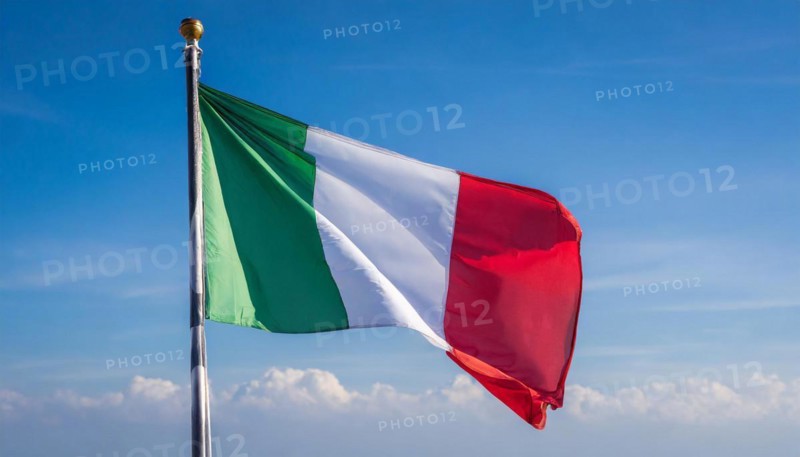 The flag of Italy flutters in the wind, isolated against a blue sky