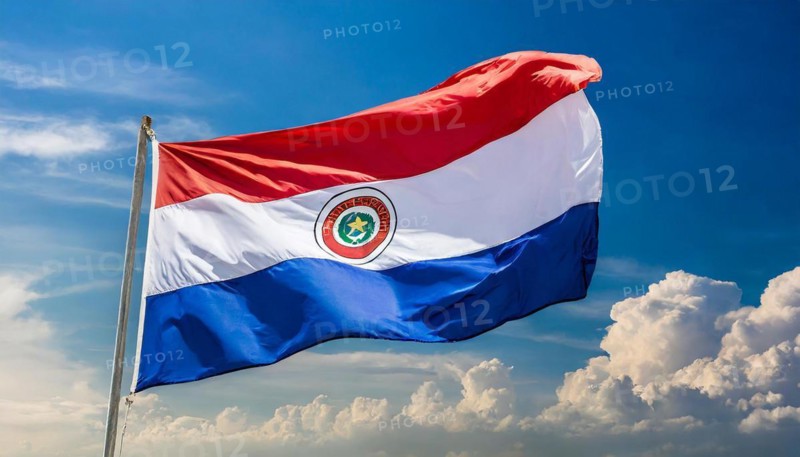 The flag of Paraguay flutters in the wind, isolated against a blue sky