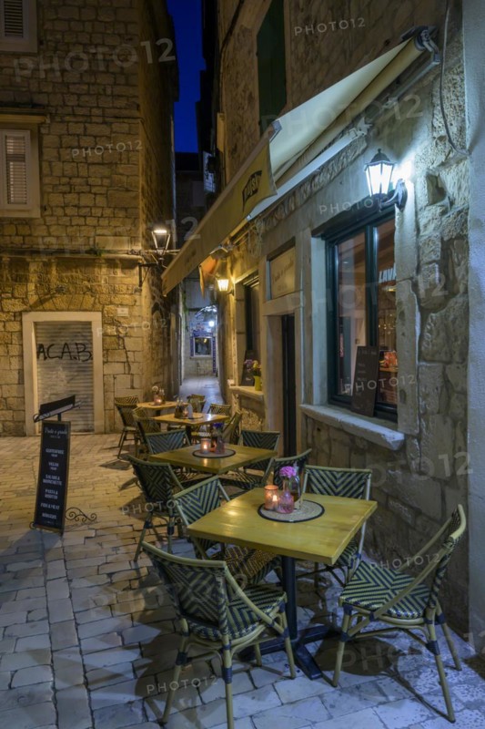 Empty cafe with tables on a cobblestone path at night, Trogir, Dalmatia, Croatia, Europe