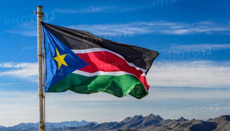 The flag of South Sudan, fluttering in the wind, isolated, against the blue sky