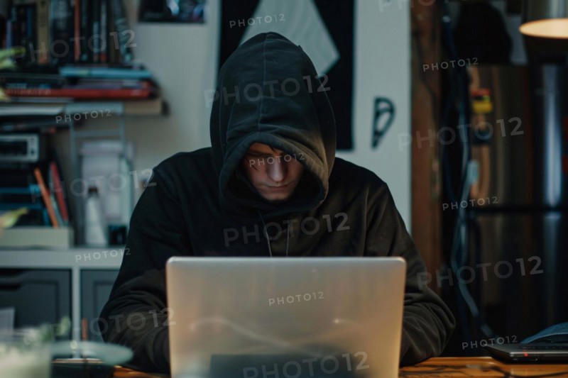 Man covering his face with hoodie in front of laptop. KI generiert, generiert, AI generated