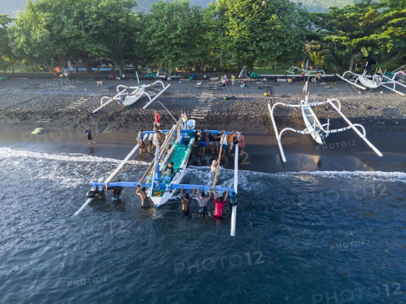 Fishermen unload their catch from their outrigger boat in the morning. Amed, Karangasem, Bali, Indonesia, Asia
