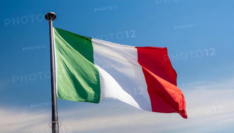 The flag of Italy flutters in the wind, isolated against a blue sky