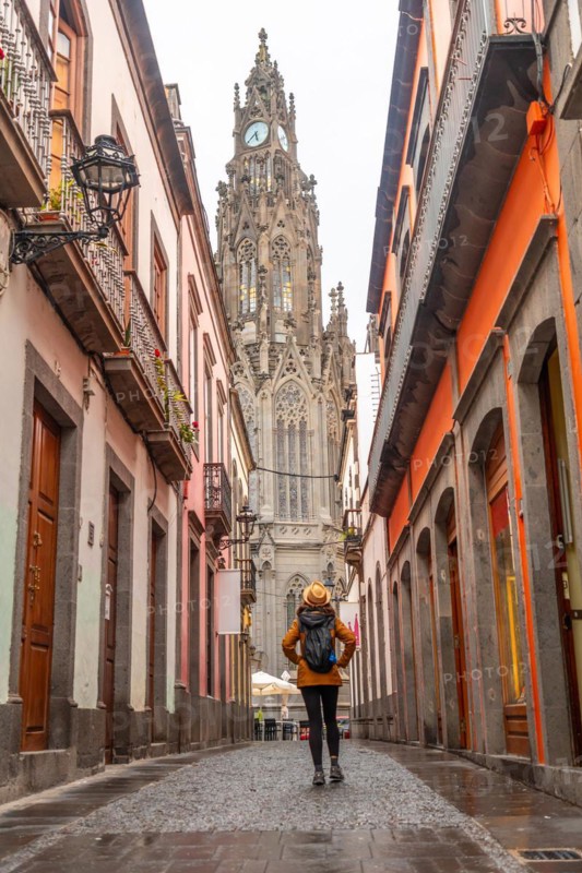 A tourist woman walking along a beautiful street next to the Church of San Juan Bautista, Arucas Cathedral, Gran Canaria, Spain, Europe