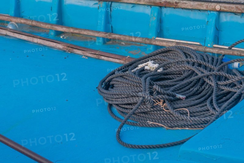 Black rope coiled up in bottom of blue fishing boat in South Korea