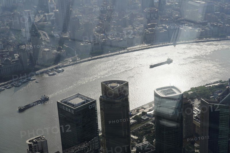 View from the 632 metre high Shanghai Tower, nicknamed The Twist, Shanghai, People's Republic of China, The sun shines through the skyscrapers onto a busy river, Shanghai, China, Asia