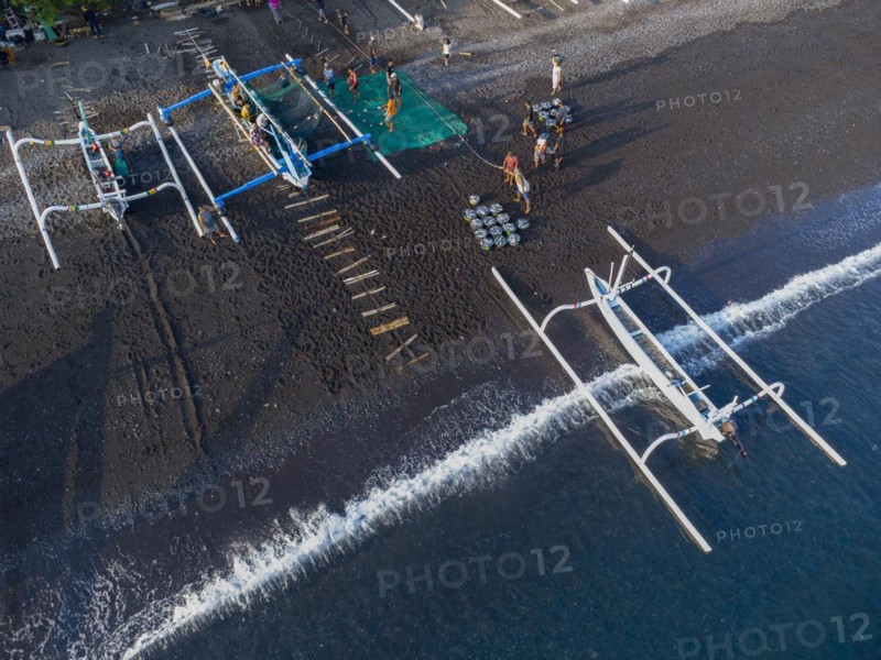 Fishermen unload their catch from their outrigger boat in the morning. Amed, Karangasem, Bali, Indonesia, Asia