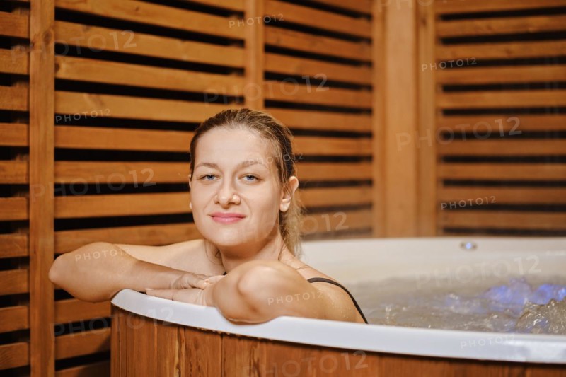 Smiling mid adult woman leaning on the edge of hot tub while evening relaxation in water
